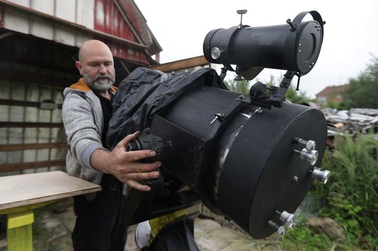 Muž manipuluje s veľkým astronomickým teleskopom vonku