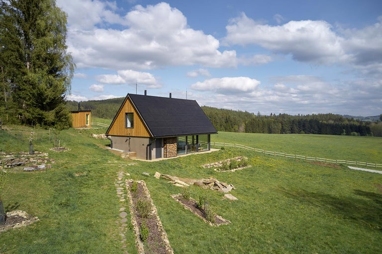 Vonkajší pohľad na moderný dom so solárnou strechou vo vidieckom prostredí.