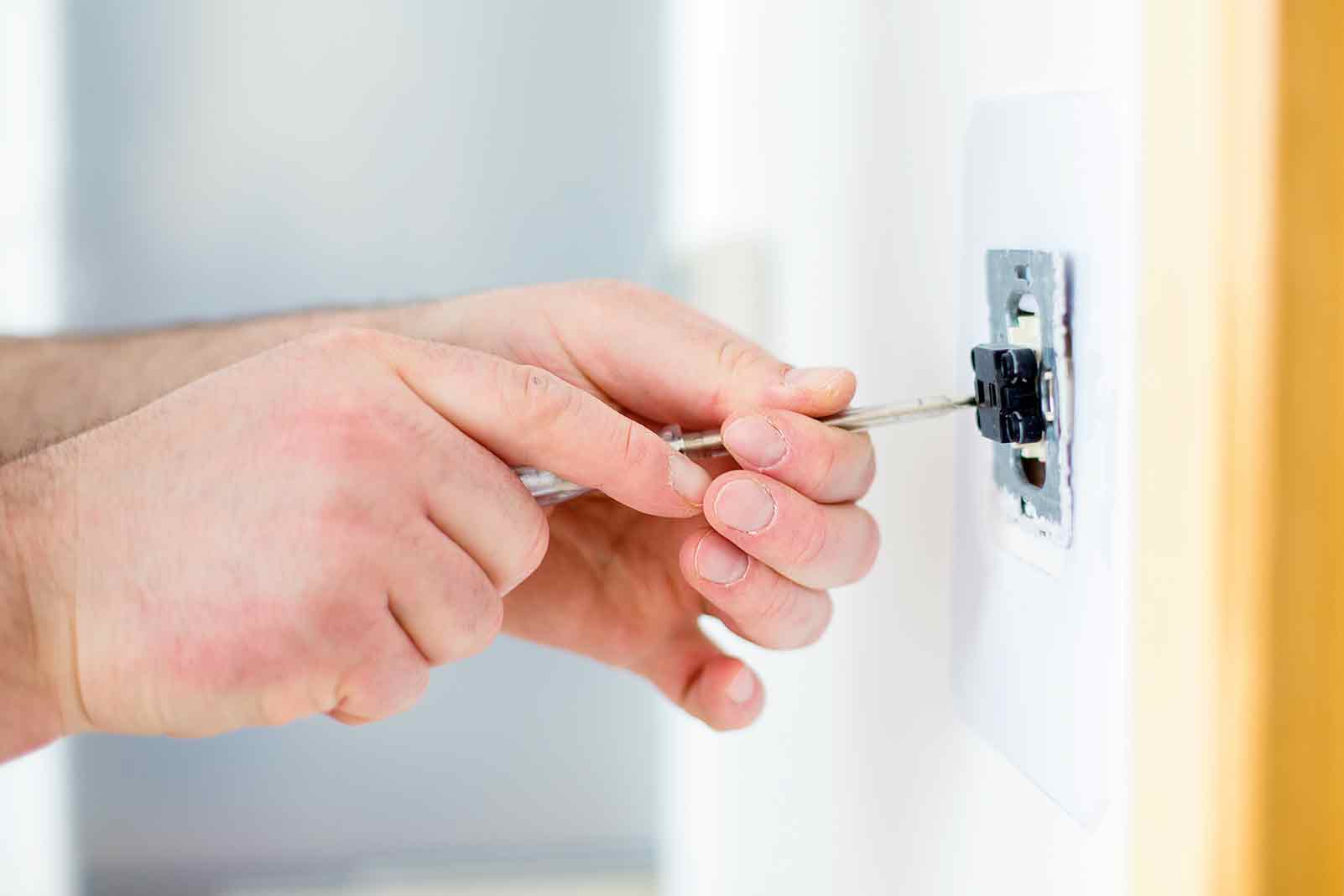 Elektrikár montuje vypínač svetla pomocou skrutkovača.