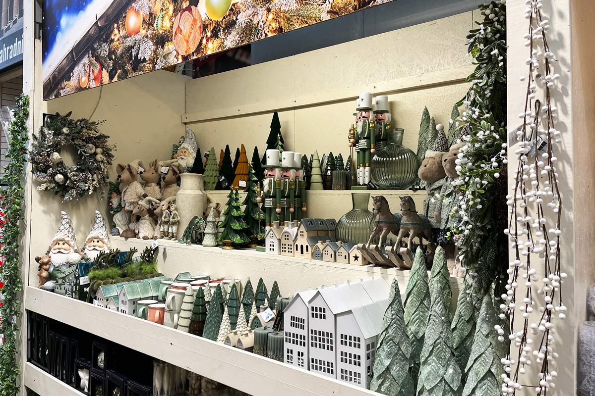 Dekoratívna vianočná scéna s figúrkami, stromami a domami v regáli