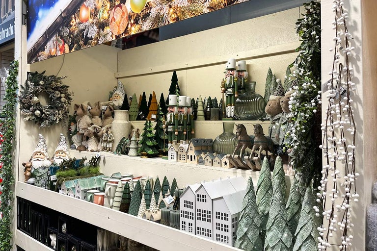 Dekoratívna vianočná scéna s figúrkami, stromami a domami v regáli