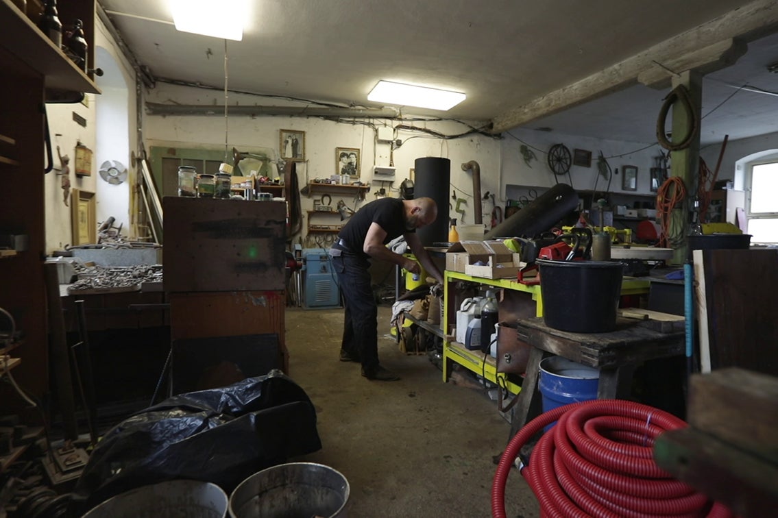 Dielňa s náradím, materiálmi a osobou pracujúcou na regáli