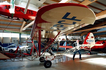 Letecký hangár s niekoľkými lietadlami a jednou osobou