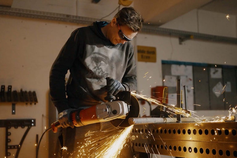 Muž brúsi kov uhlovou brúskou, lietajú iskry