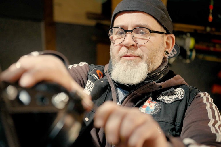 Muž s bradou, okuliarmi a čiapkou montuje výrobok