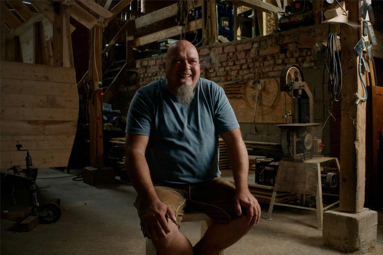 Portrét muža v dielni s drevenými trámami a náradím