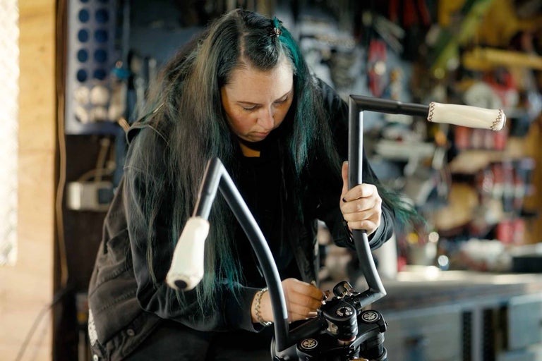 Žena montuje riadidlá motocykla v dielni