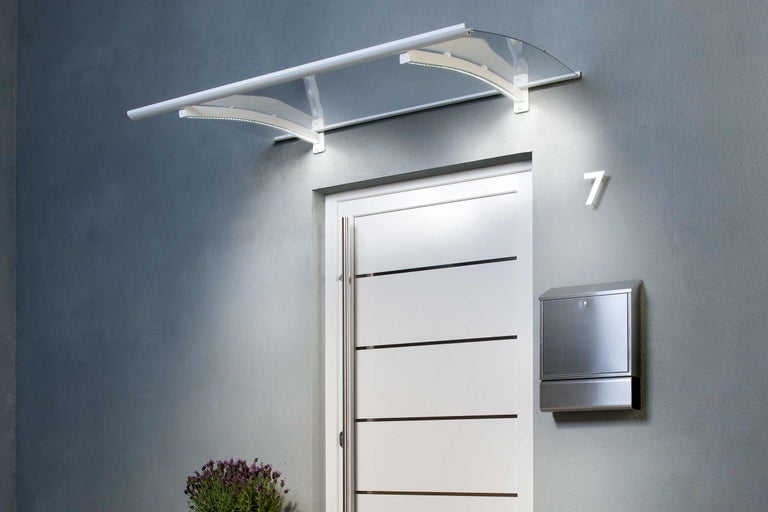 Strieška s osvetlením nad vchodovými dverami s poštovou schránkou a číslom domu.