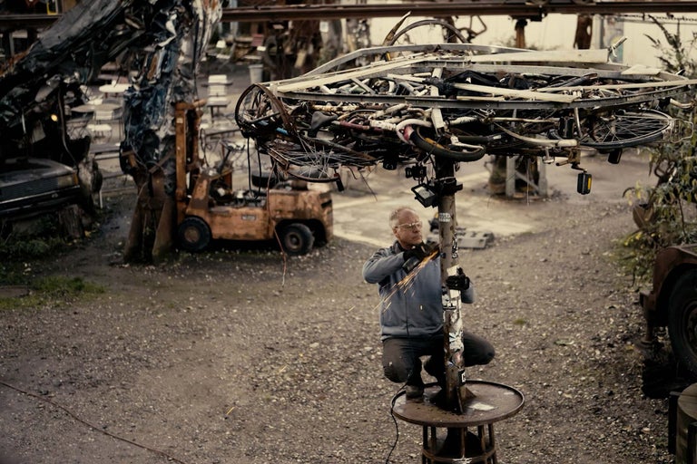 Muž pracuje s rozbrusovacou pílou na kovovom stĺpiku pod tienidlom z kovového šrotu.