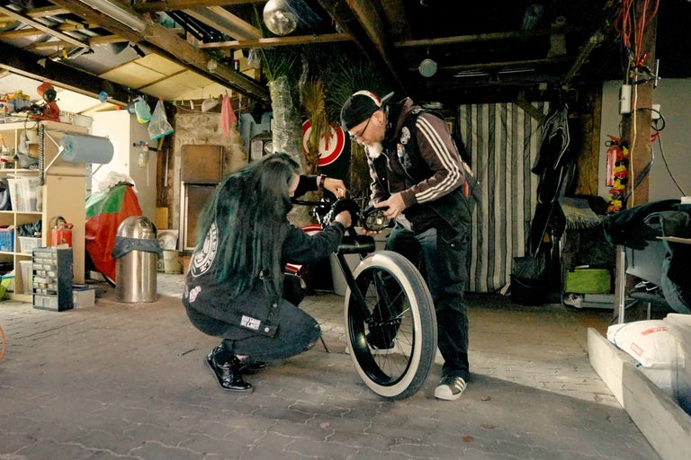 Dvaja ľudia opravujú bicykel v garáži.