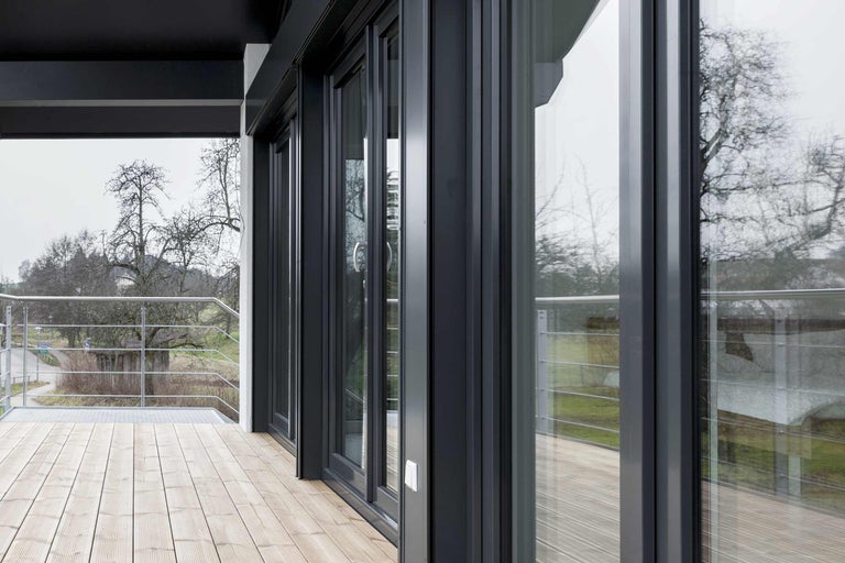 Viacdielny systém posuvných dverí zo skla a hliníka na terase s drevenou podlahou