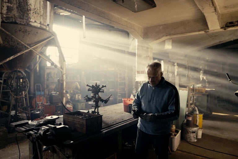 Dielňa s pracovným stolom, náradím a pracujúcim mužom