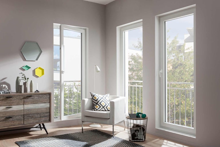 Svetlá obývacia izba s bielymi plastovými oknami, kreslom a komodou