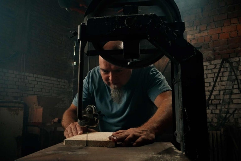 Muž reže drevo pásovou pílou