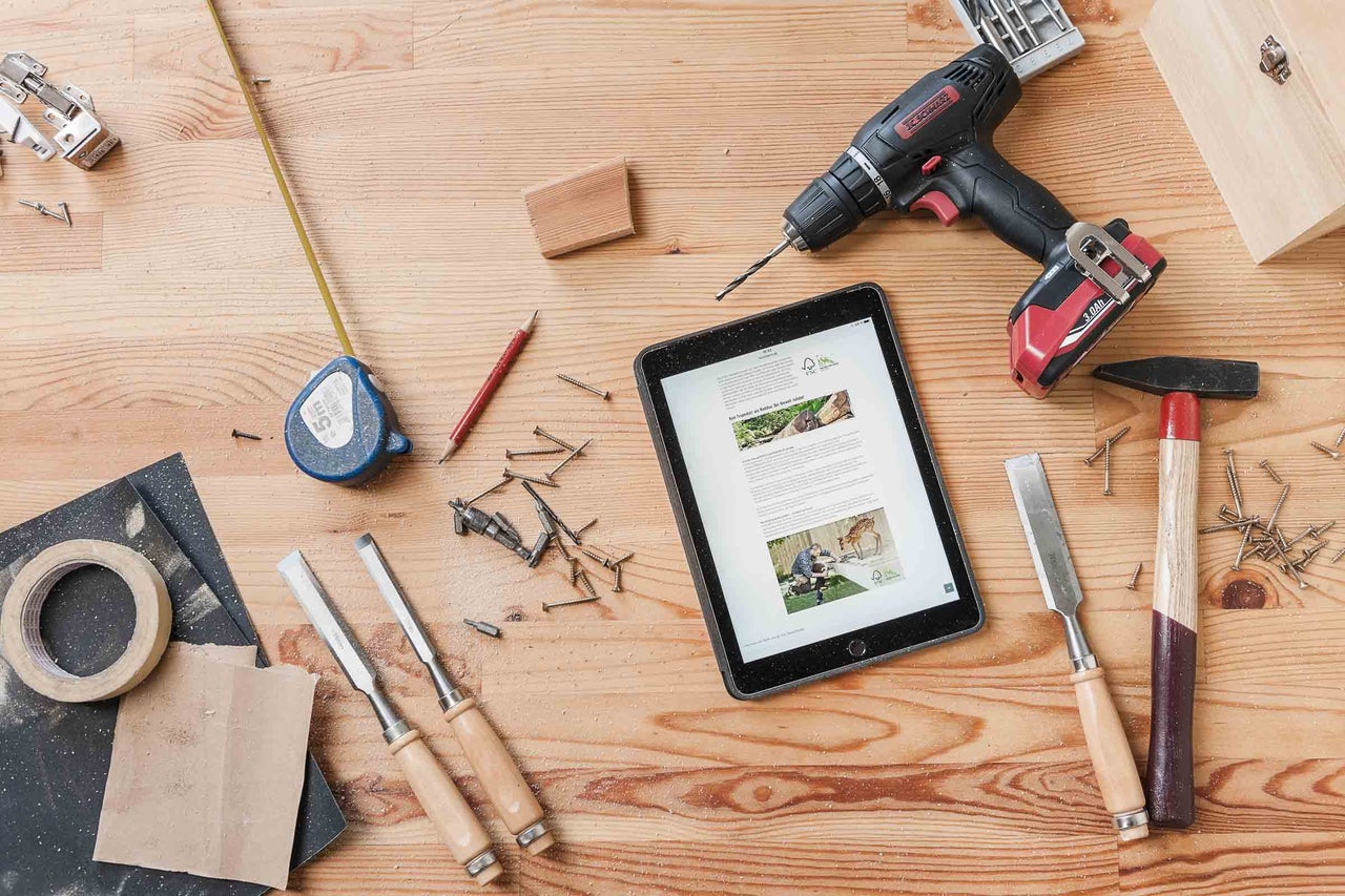 Pohľad zhora na pracovný stôl s náradím, tabletom a stavebnými materiálmi