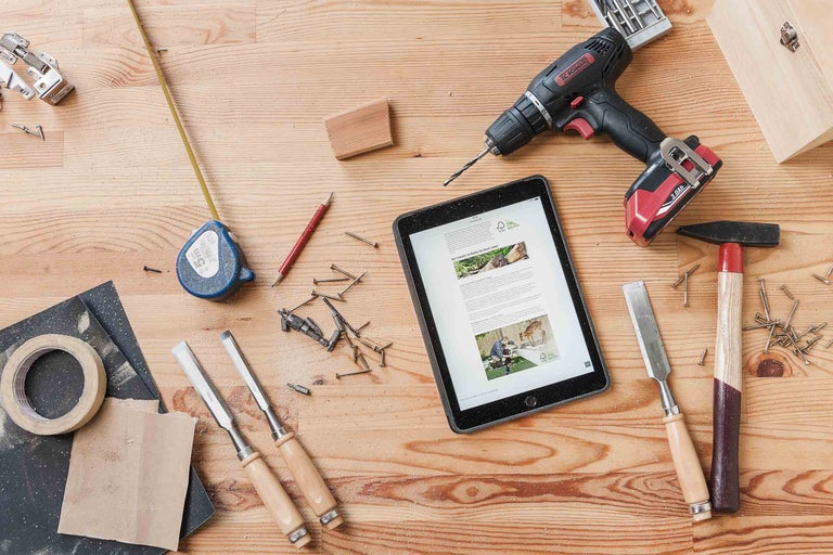 Pohľad zhora na pracovný stôl s náradím, tabletom a stavebnými materiálmi