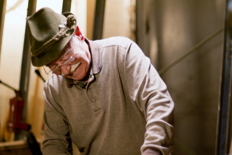 Muž s tradičným klobúkom a polokošeľou sa ohýba dole