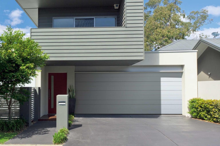 Moderný dom s šedou garážou a červenými vchodovými dverami.