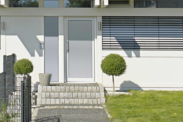 Moderný dom s vchodovými dverami, kamennými schodmi a záhradou