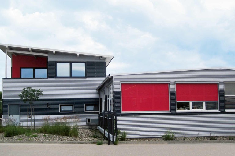 Budova s červeným systémom ochrany proti slnku pred oknami.