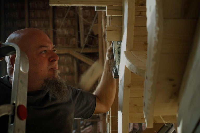 Remeselník upevňuje drevenú konštrukciu sponkovačkou