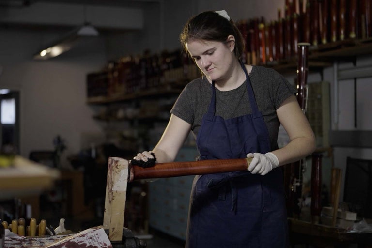 Žena opracováva drevenú tyč v dielni