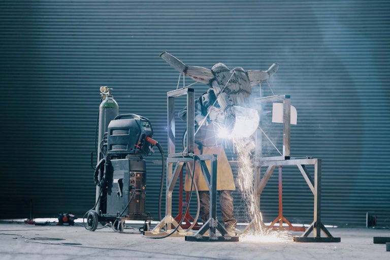 Zvárač pracuje na kovovej soche so zváracím zariadením