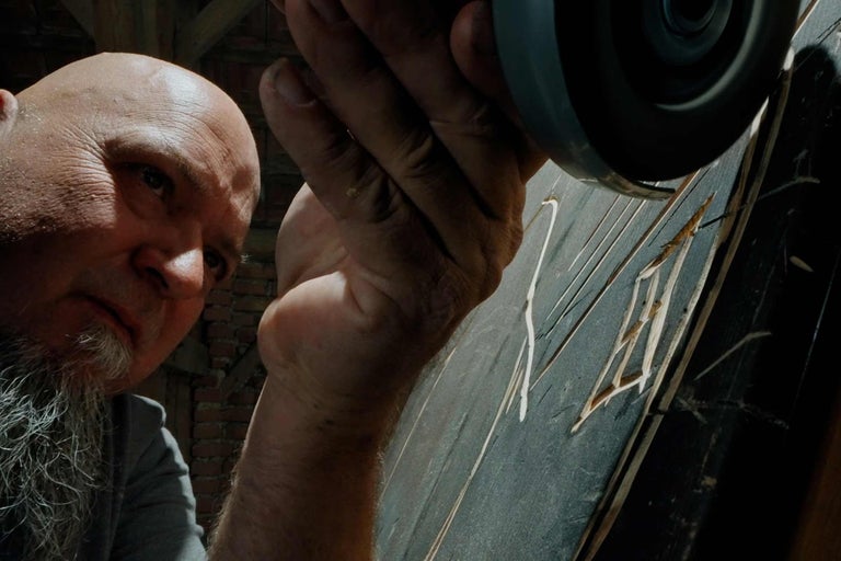 Muž pracuje s uhlovou brúskou na drevenom obrobku.