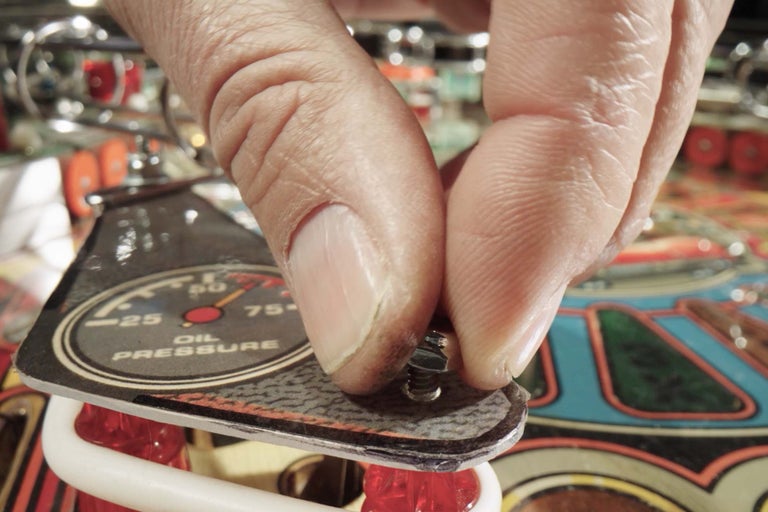 Osoba pripevňuje kryt s ukazovateľom tlaku oleja na fliper.