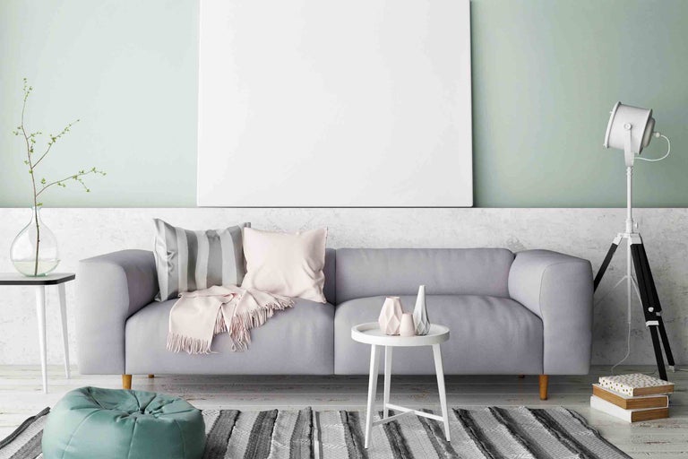 Obývacia izba s pohovkou, vankúšmi, kobercom a lampou