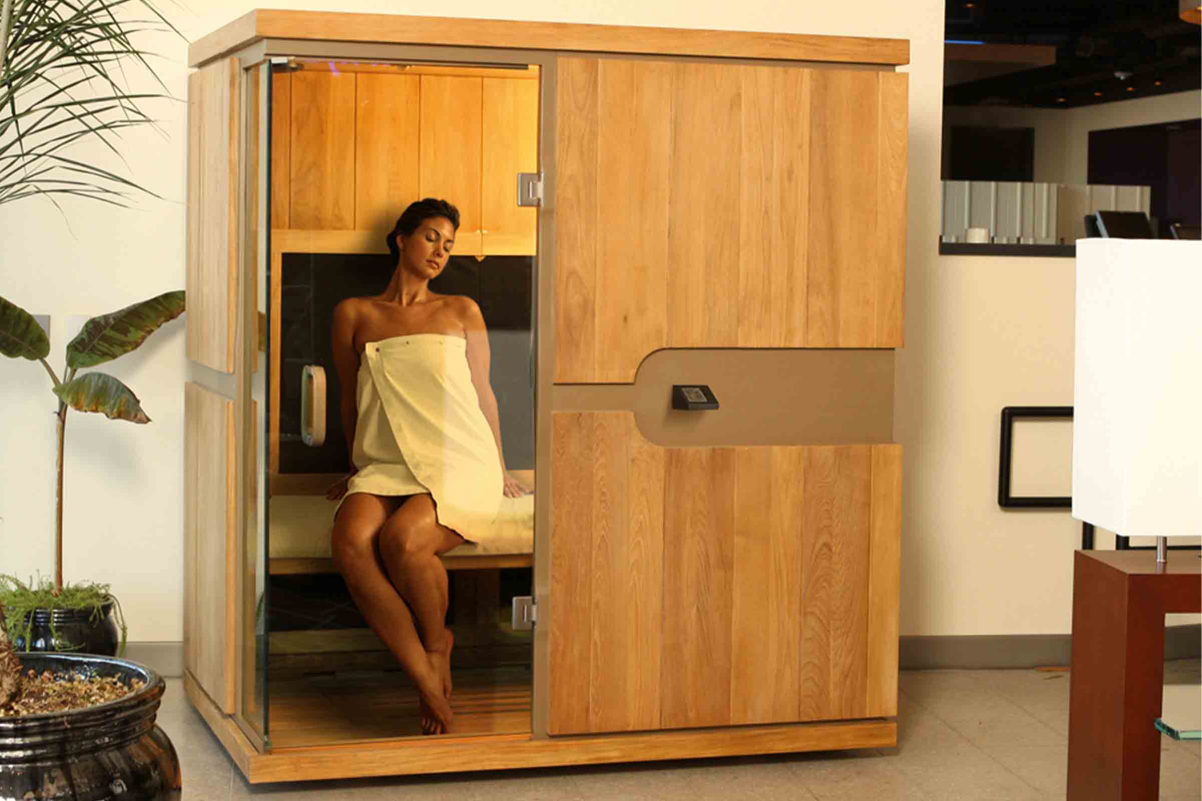 Drevená sauna so sklenenými dverami a ženou s uterákom