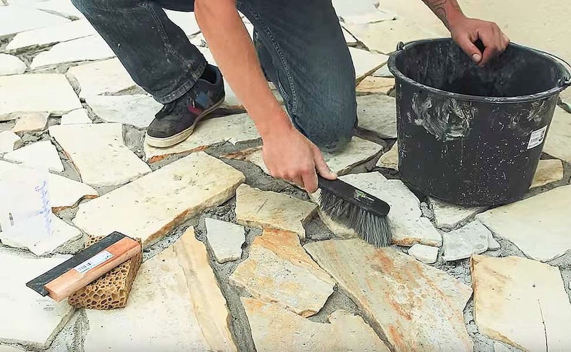 Pokládka dlažby z prírodného kameňa pomocou škárovacej hmoty a náradia.