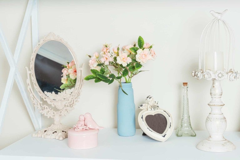 Dekoratívne aranžmán so zrkadlom, kvetmi, fotorámikom a svietnikom na povrchu