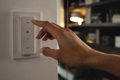 Ruka ovláda vypínač svetla Philips na stene.