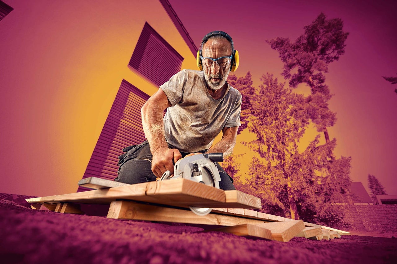 Remeselník pracuje s ručnou okružnou pílou na drevených latách a pritom nosí ochranné vybavenie.