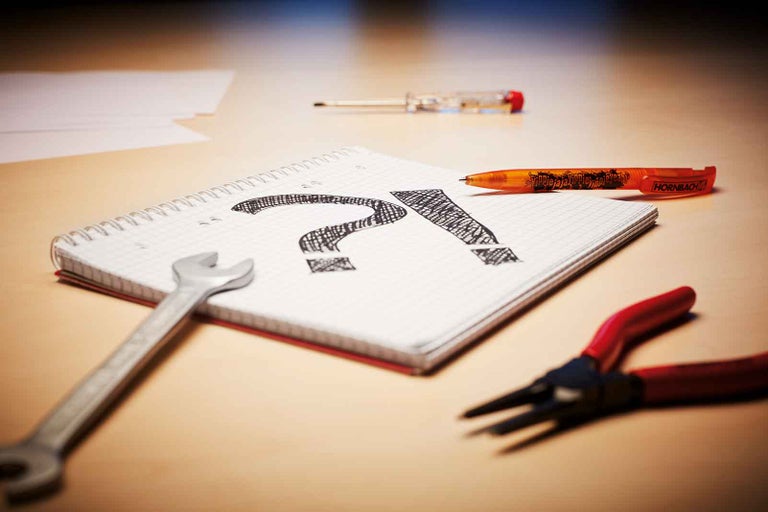 Scéna s kľúčom, kliešťami, skrutkovačom, perom a poznámkovým blokom s otáznikom