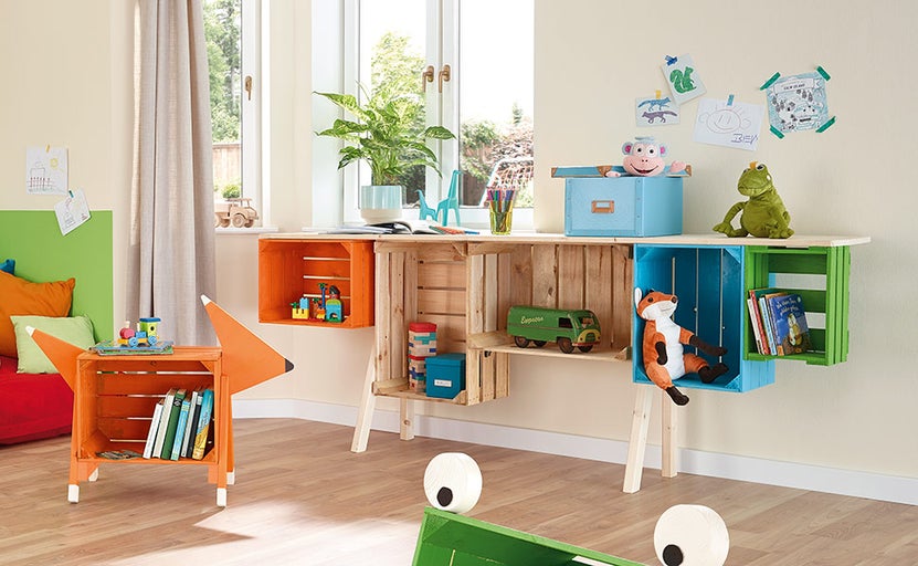 Detská izba s písacím stolom a regálmi z drevených debien s hračkami a dekoráciou