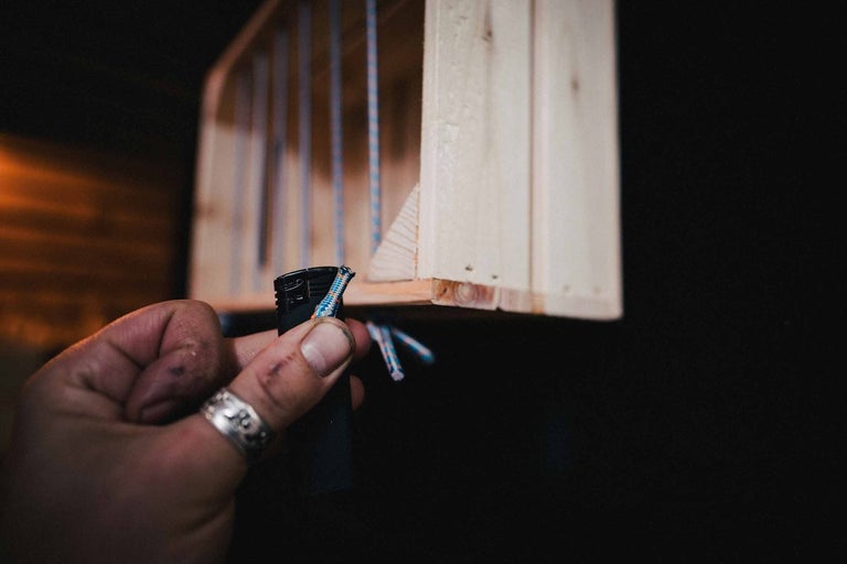 Ruka zatavuje lano zapaľovačom na drevenej polici