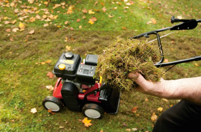 Prevzdušňovač trávnika na trávniku s machom v ruke