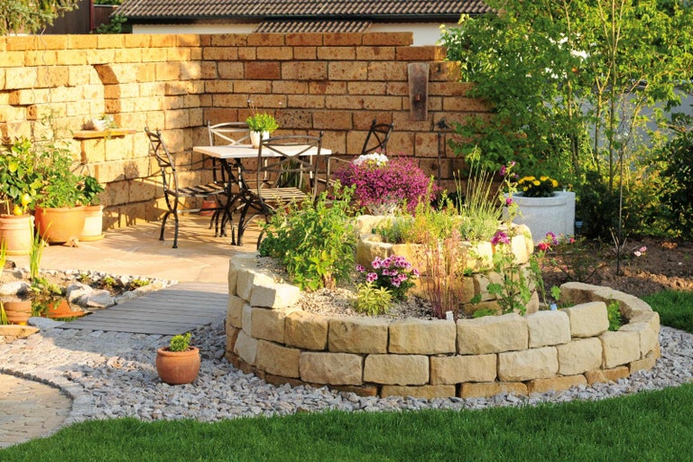 Záhradná scéna s kamennou stenou, skalkou a posedením