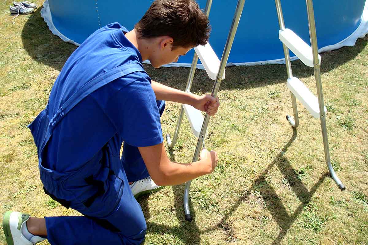 Muž montuje bazénový rebrík na záhrade