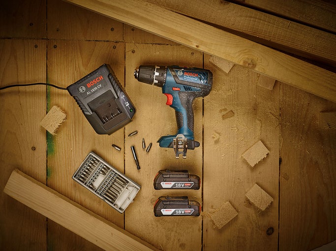 Sada akumulátorového skrutkovača s nabíjačkou, akumulátormi a sadou bitov na drevenom povrchu