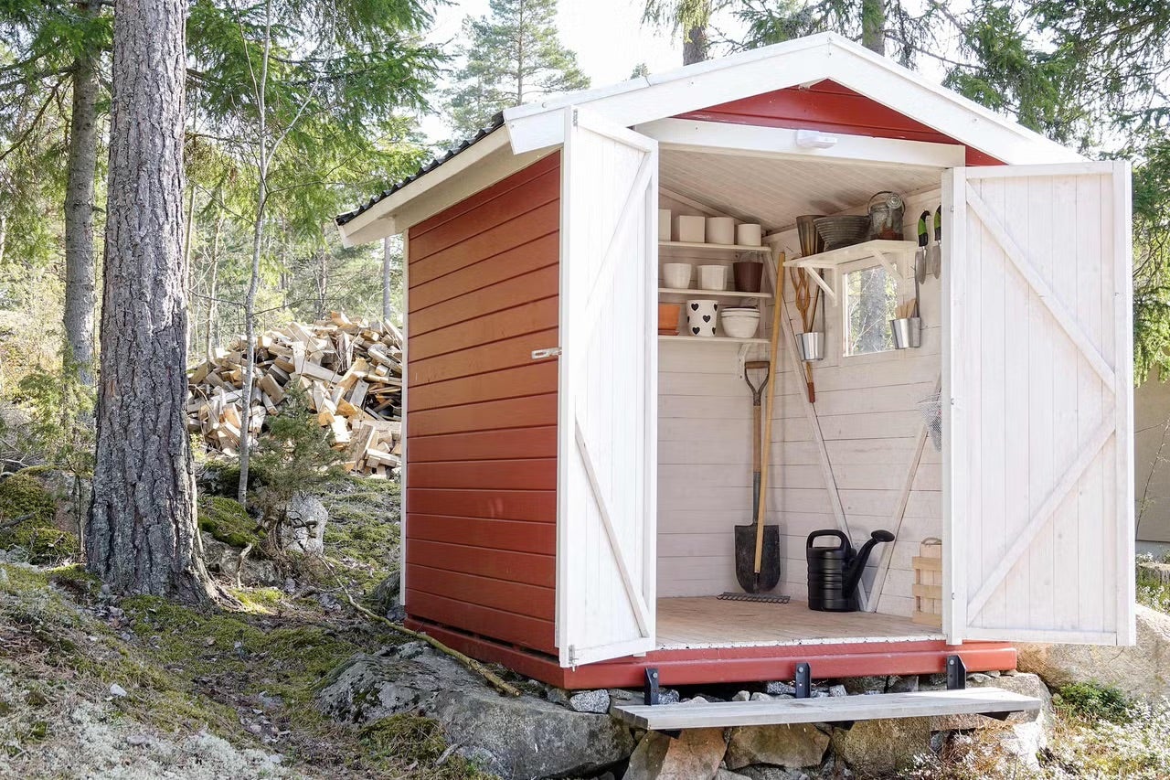 Záhradná búda s otvorenými dverami a záhradným náradím