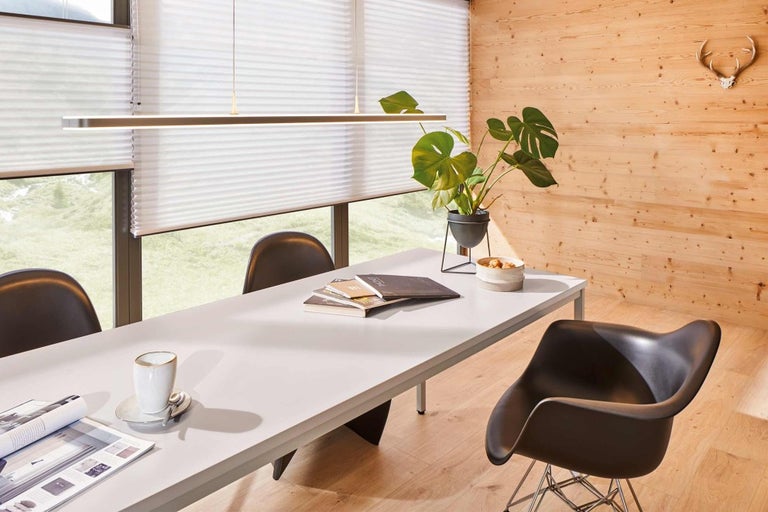 Jedáleň s jedálenským stolom, stoličkami, závesnou lampou a okennými žalúziami pre svetlé prostredie.