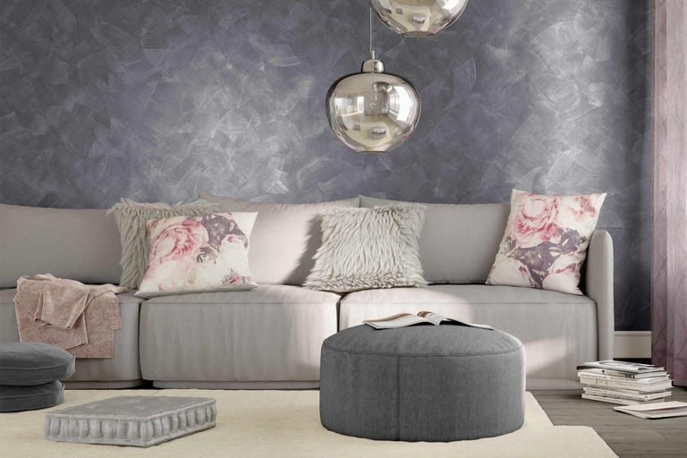 Obývacia izba so sivou pohovkou, vankúšmi, pufom a dekoratívnou nástennou dekoráciou