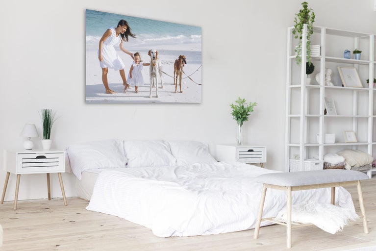 Svetlá spálňa s posteľou, nočnými stolíkmi, regálom a plátenným obrázkom na stene