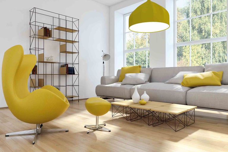 Obývacia izba s pohovkou, kreslom, knižnicou a závesným svietidlom pre svetlú, usporiadanú atmosféru