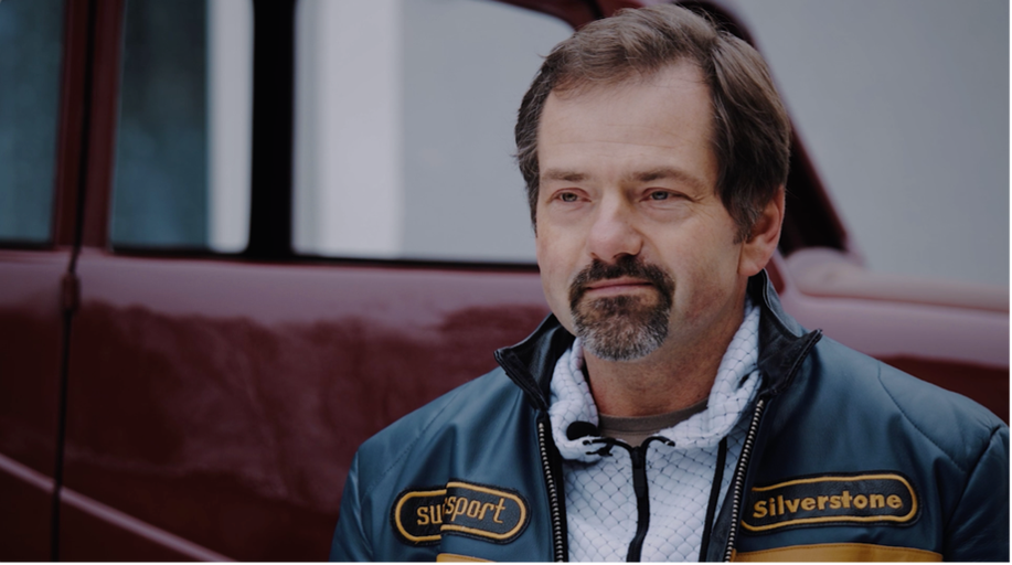 Muž s bundou pred červeným vozidlom