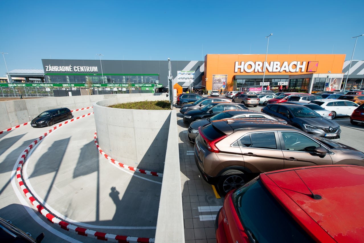 Predajňa Hornbach s veľkým parkoviskom, záhradným centrom a modernou architektúrou za jasného denného svetla. Hornbach Logo na fasáde.