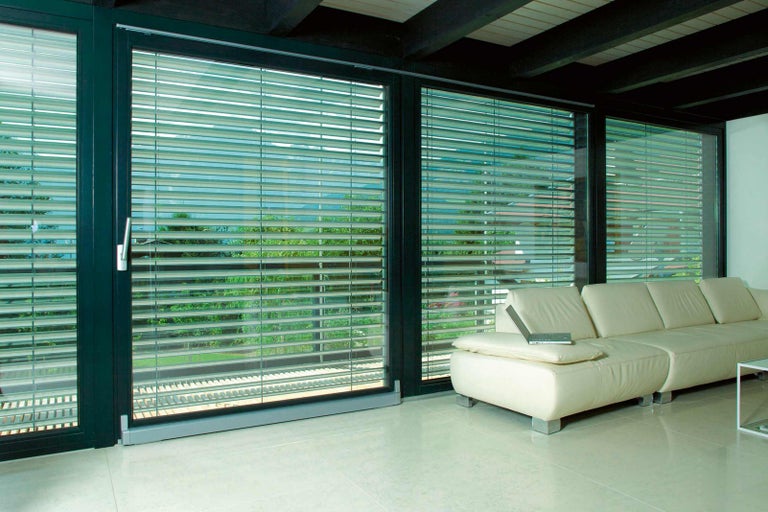 Interiér s presklenou stenou a horizontálnymi žalúziami na reguláciu svetla
